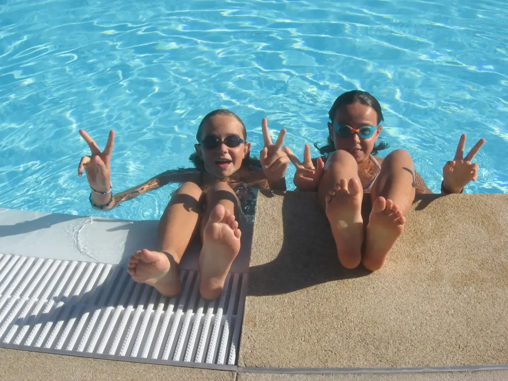 Deux enfants souriants au bord d'une piscine bleue