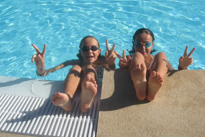 Deux enfants souriants au bord d'une piscine bleue