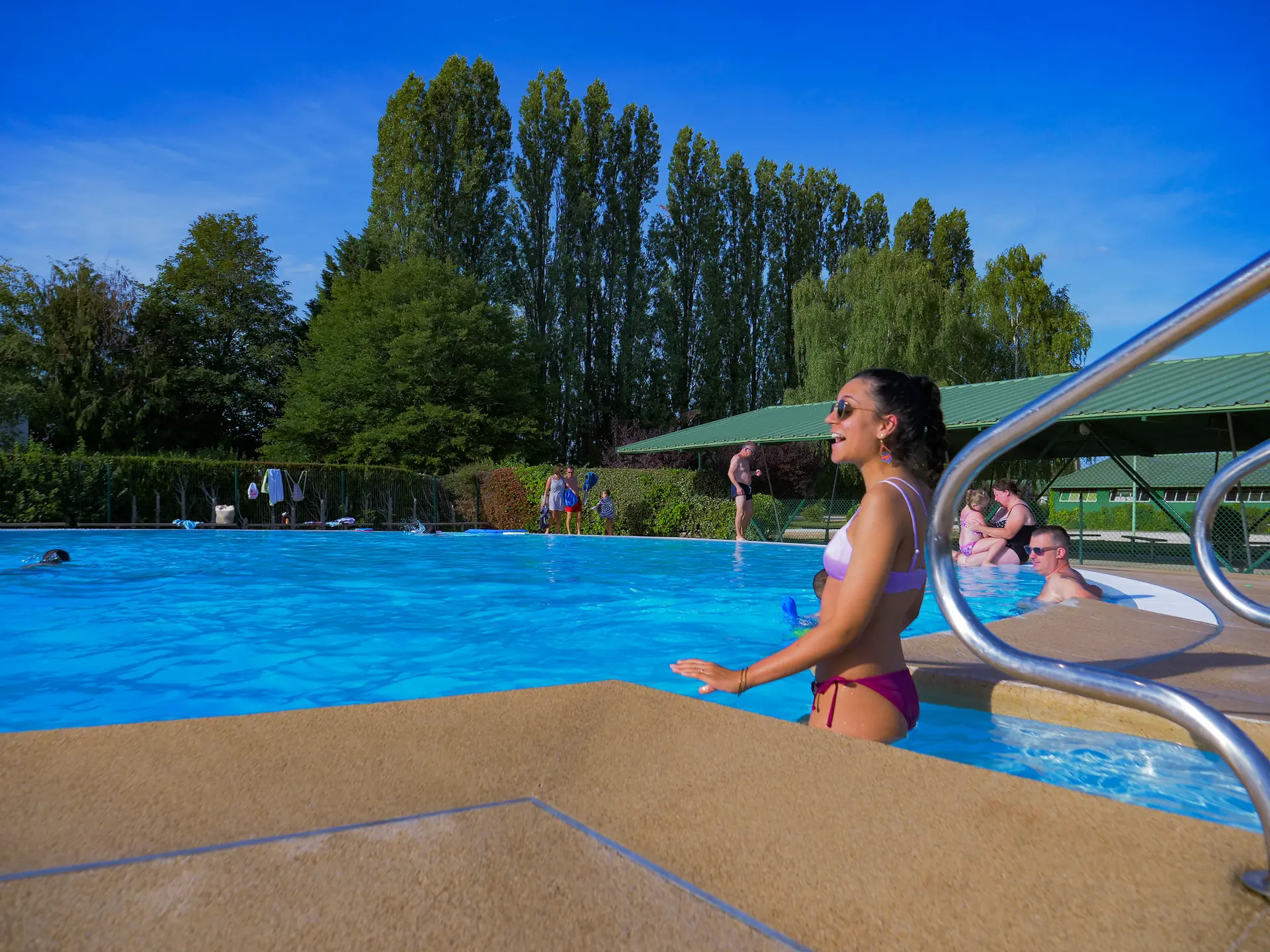 Jeune femme en bikini au bord d'une piscine extérieure ensoleillée