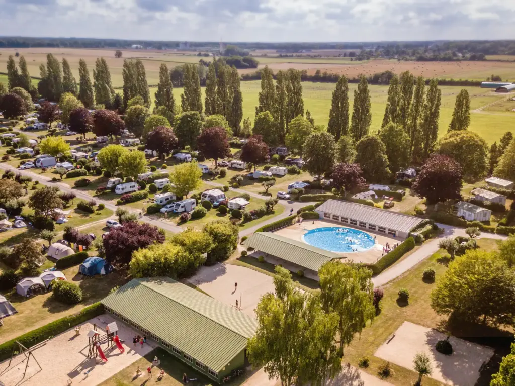 Vue aérienne d'un camping verdoyant avec piscine en France
