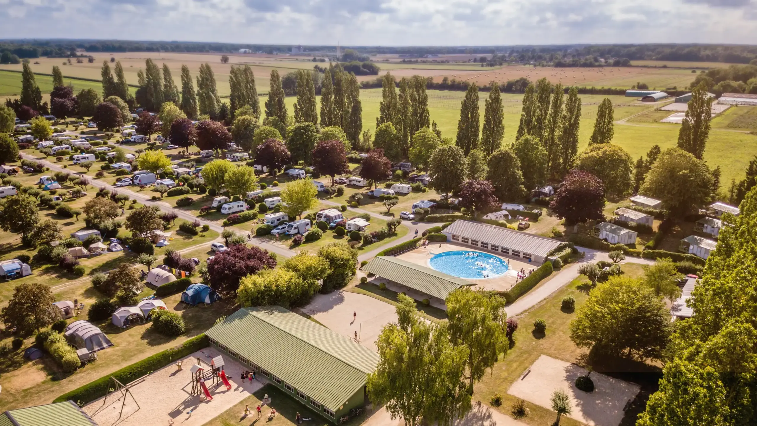 Vue aérienne d'un camping verdoyant avec piscine en France